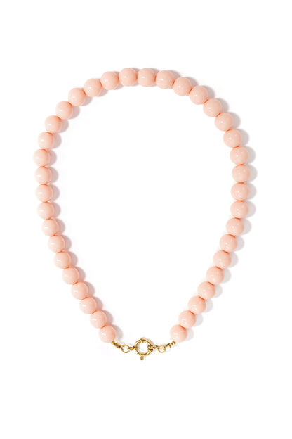 A minimalist necklace of light pink resin beads with a gold-toned circular clasp on a white background.