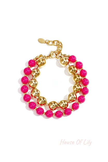 Double layered bracelet with bright pink acrylic and gold-tone beads on white background