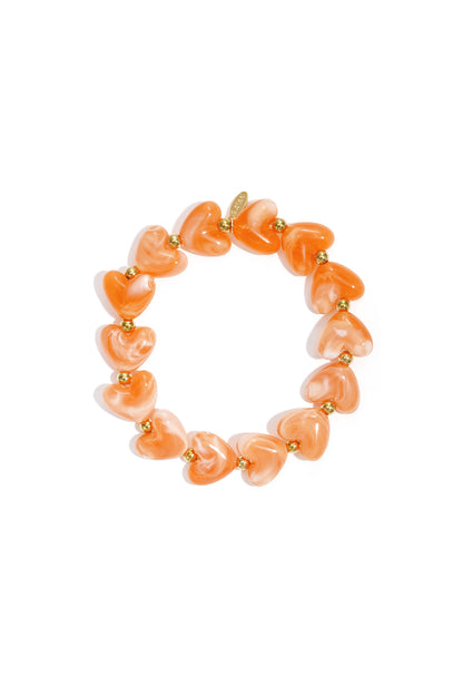 Stretch bracelet featuring orange marbled heart-shaped beads alternating with small gold metallic accent beads.