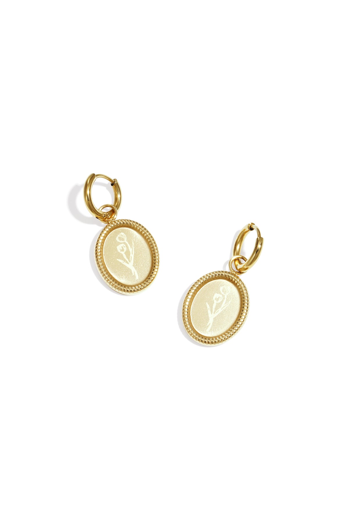 Pair of gold oval hoop earrings with embossed floral design on white background