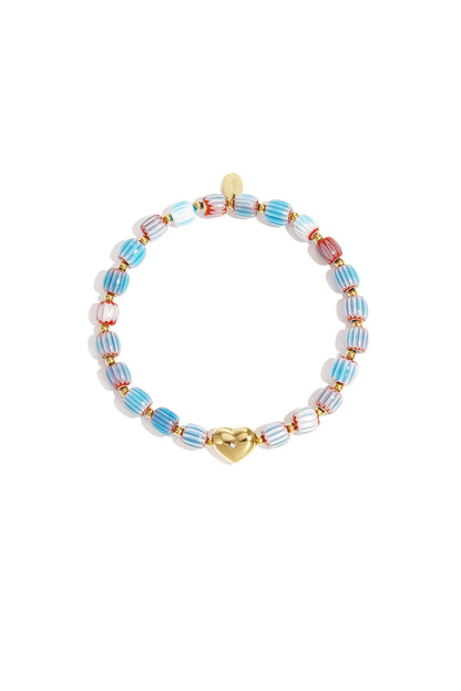 Light blue, red, and white striped beaded bracelet with gold heart charm laid flat on white background