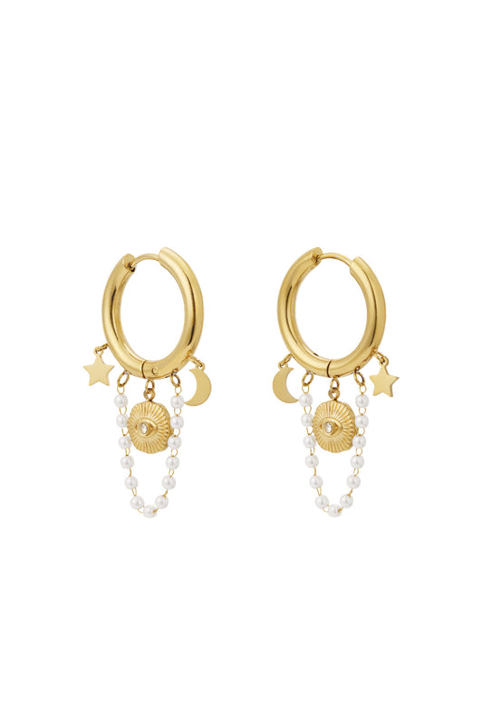 Pair of gold celestial charm hoop earrings with star, moon, sun motifs and pearl chain charms displayed on white background