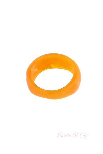 Close-up of bright orange marbled resin bangle bracelet on white background