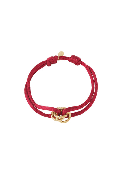 Red knot charm bracelet with gold-plated twisted knot pendant on white background