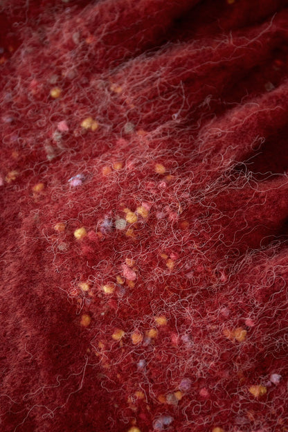 Close-up macro shot of brick red fabric showing fluffy yarn and colorful confetti details