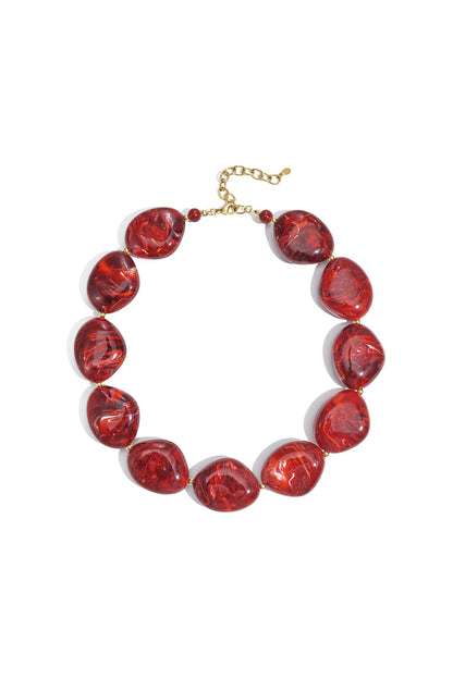 Chunky red marbled acrylic beaded necklace laid flat with gold chain extender