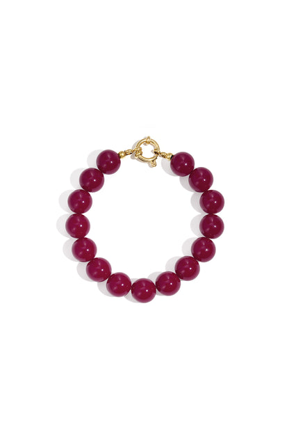Dark red resin bead bracelet with gold toggle clasp on white background