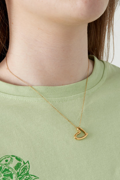Close-up of woman wearing the gold heart pendant necklace with a light green top