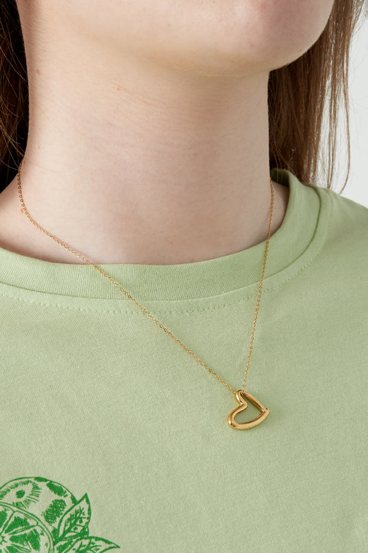 Close-up of woman wearing the gold heart pendant necklace with a light green top