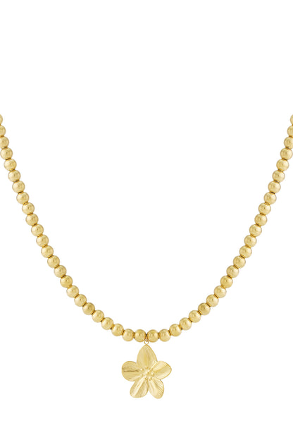 Close-up of gold beaded necklace with flower pendant on white background