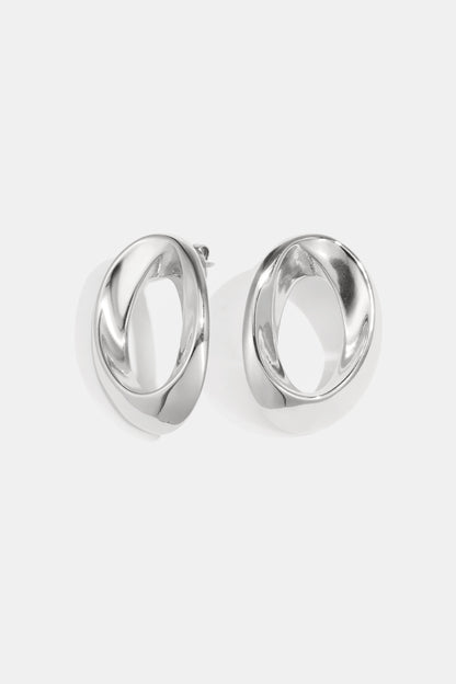 Pair of polished silver-tone twisted oval hoop earrings on white background