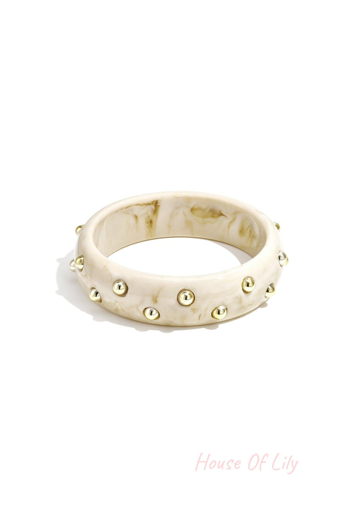 Cream marble resin bangle with gold studs isolated on white background