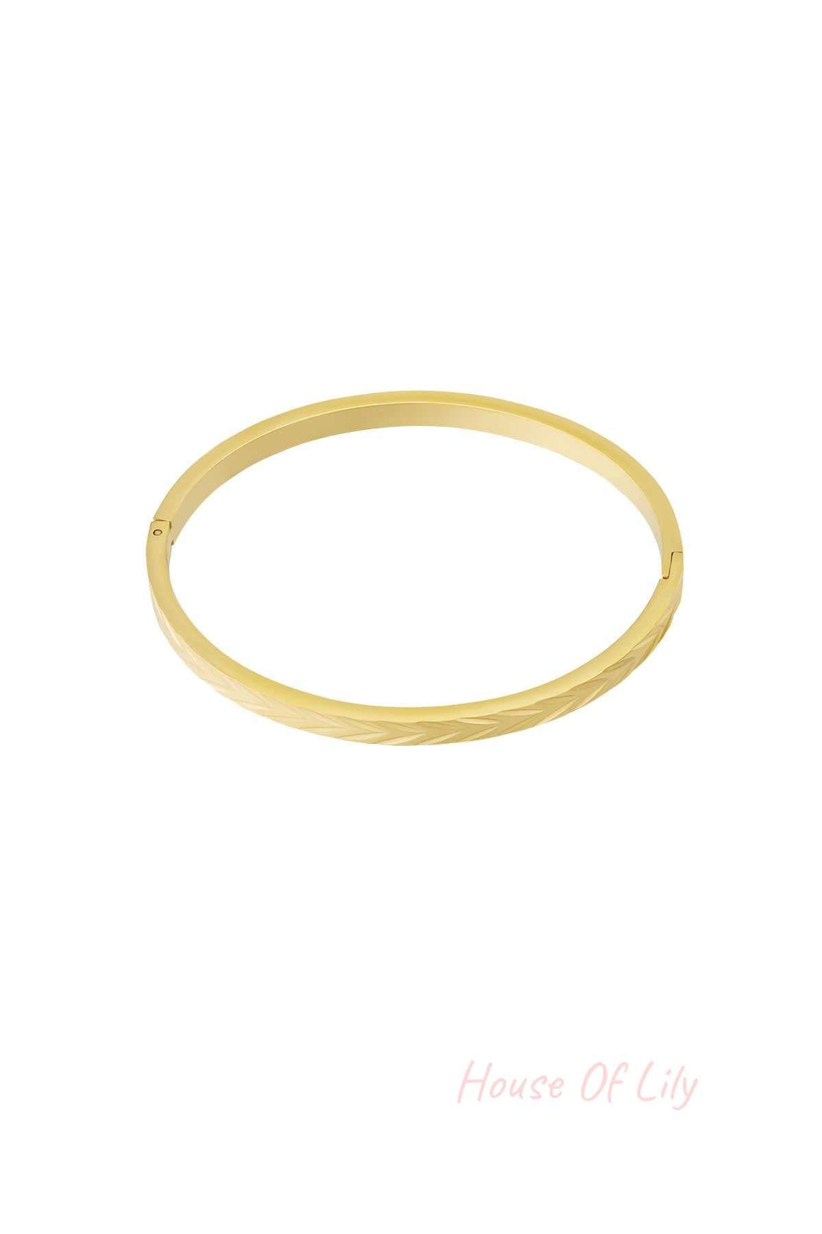 Gold-tone stainless steel bangle bracelet with embossed herringbone pattern on white background