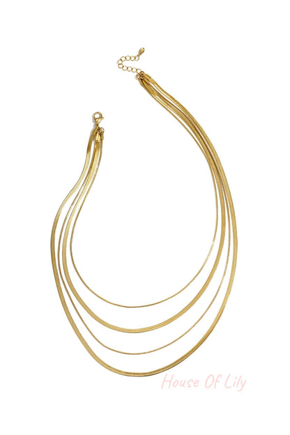 Four-strand gold layered necklace on white background with lobster clasp