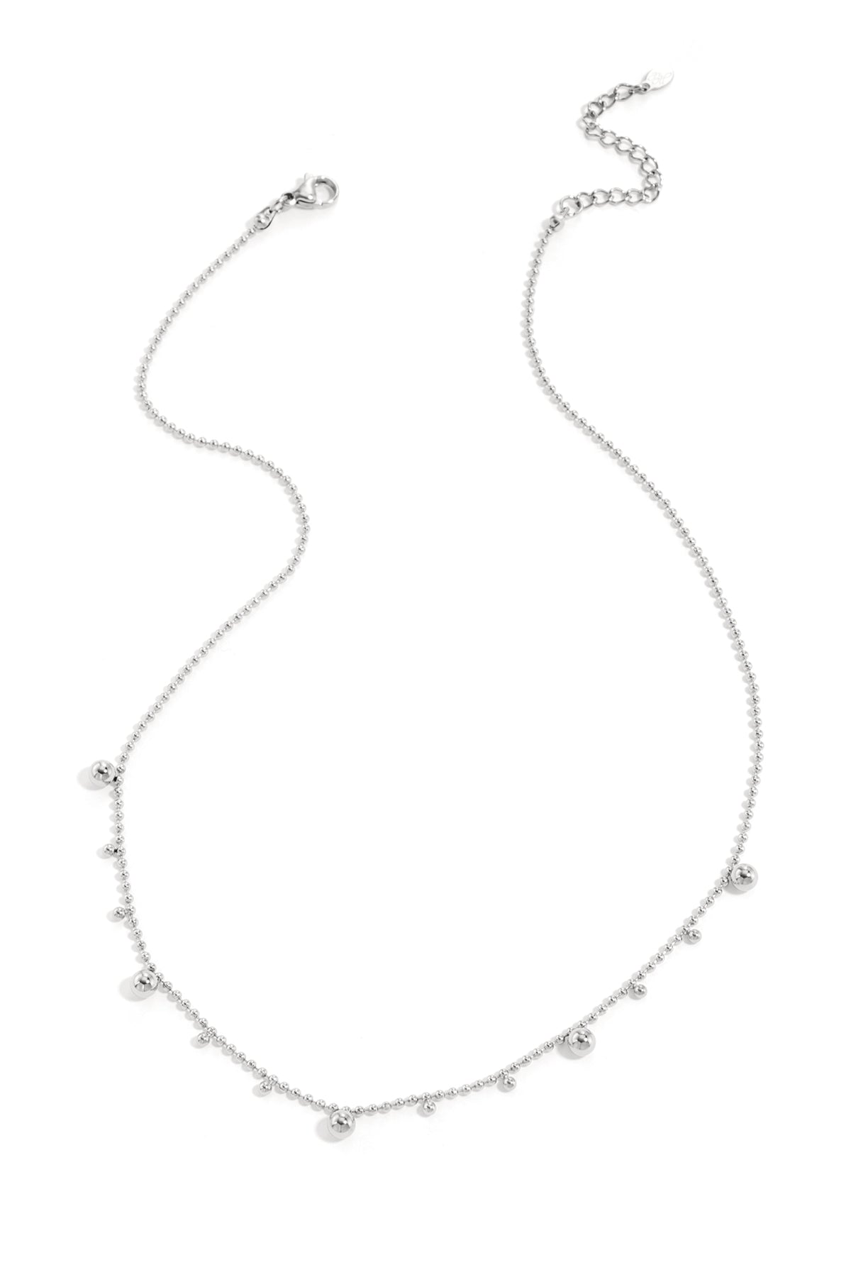 Silver tone polka dot necklace with alternating small and larger beads laid flat on white background