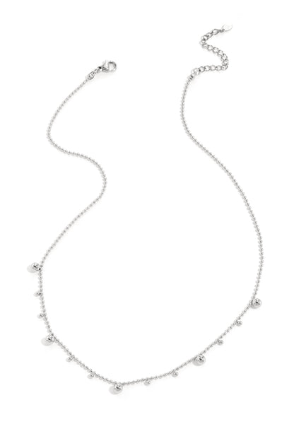 Silver tone polka dot necklace with alternating small and larger beads laid flat on white background