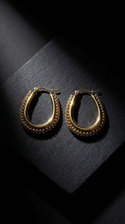 Drip Drop Glow gold U-shaped hoop earrings featuring a textured, beaded outer edge on a black textured background.
