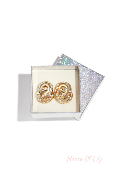 Spiraled Vibe Drops: Gold spiral earrings encrusted with baguette-cut crystals, presented in a glittery gift box.