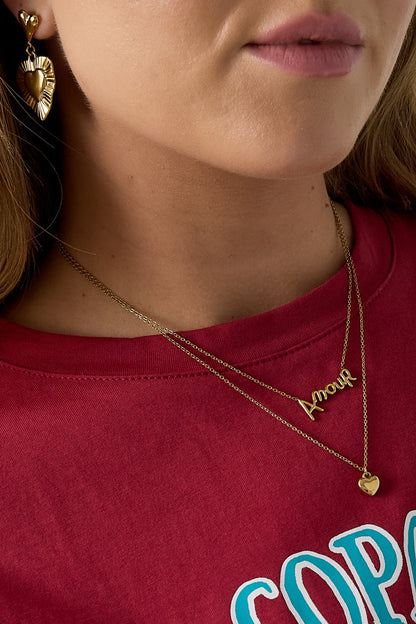 Close-up of model’s neck wearing gold layered Amour necklace and delicate heart pendant