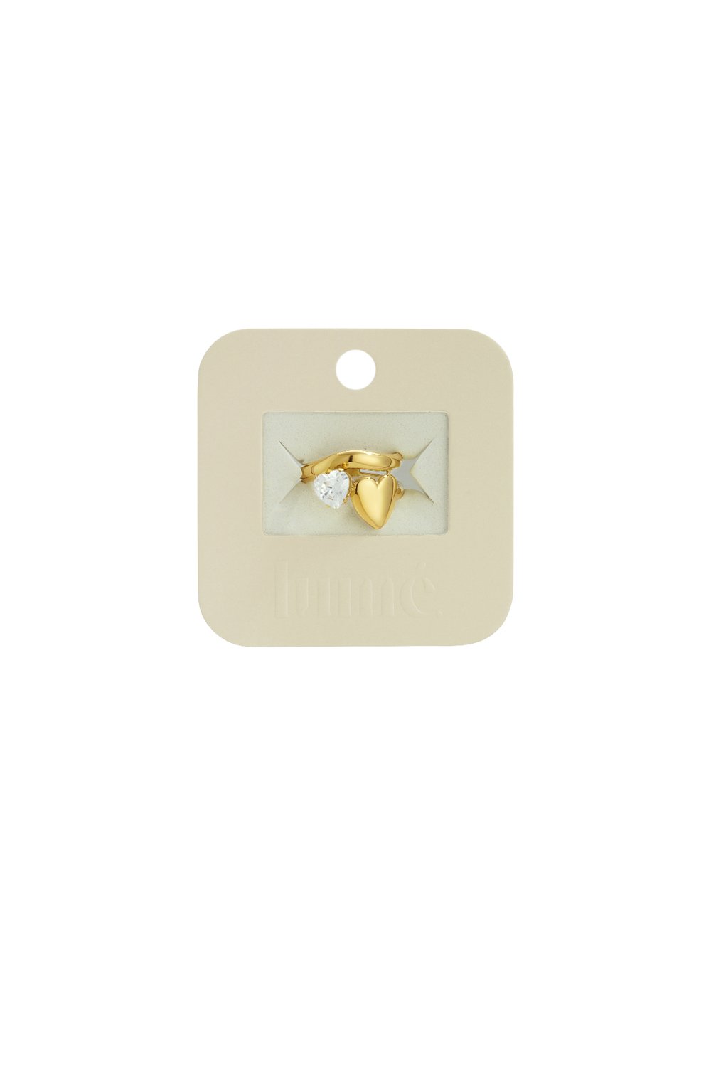 Gold-tone ring featuring a clear heart-shaped gem and a solid polished heart charm on a branded display card.