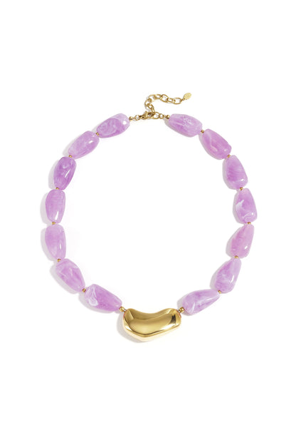Chunky beaded necklace with lavender marbled beads and a glossy gold asymmetrical centerpiece on a white background