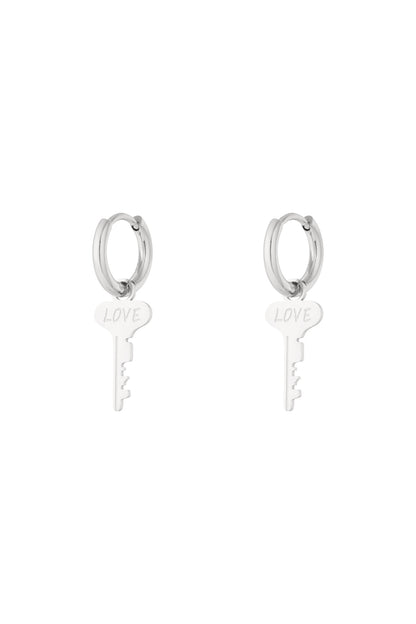 Pair of silver hoop earrings with dangling key-shaped charms engraved with the word 'LOVE' on a white background