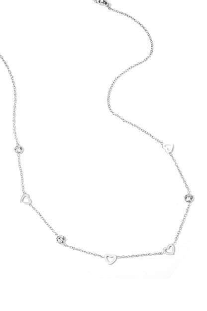Front view of a woman wearing the gold heart charm necklace paired with gold hoop earrings, showcasing the subtle sparkle