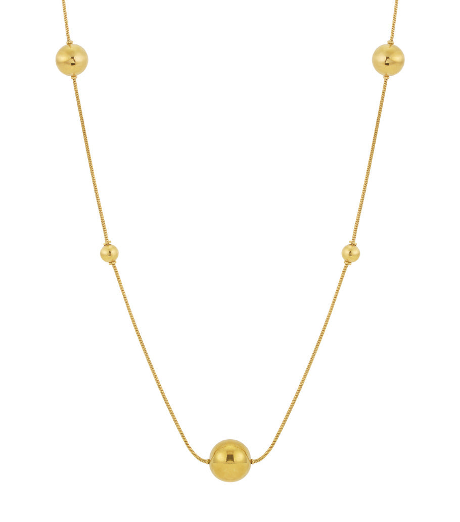 Close-up of a long gold bead necklace with polished spheres spaced evenly on a fine chain