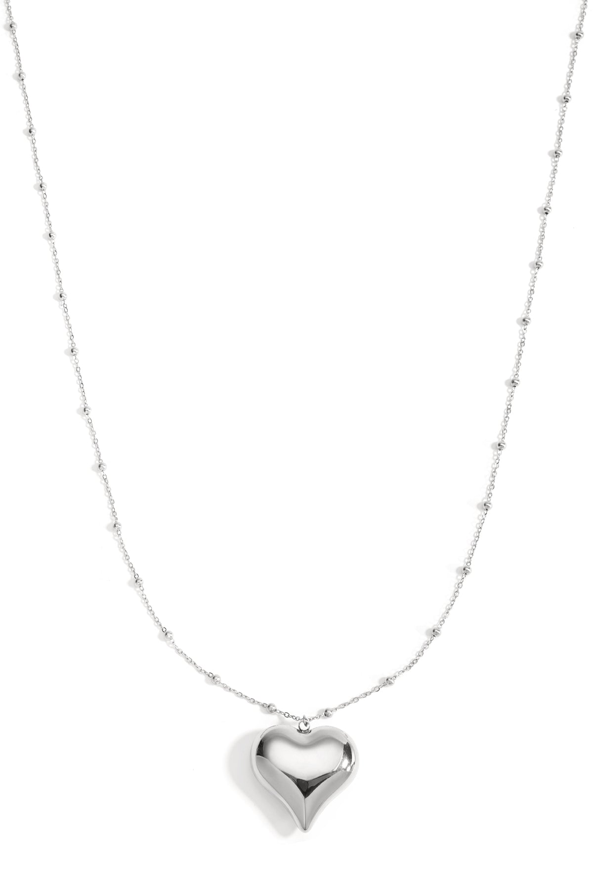 Silver long necklace with polished heart pendant and small bead details on chain, displayed on white background