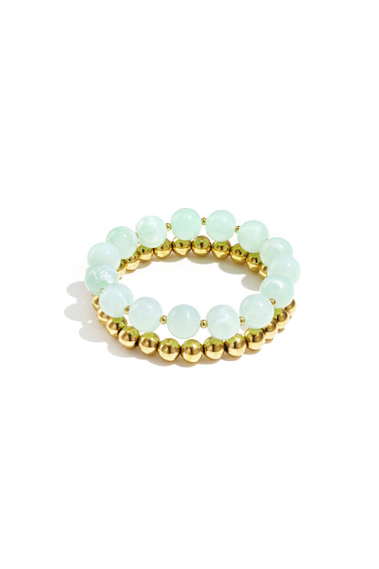 Stack of two bracelets with mint green round acrylic beads and gold-tone metal beads on white background