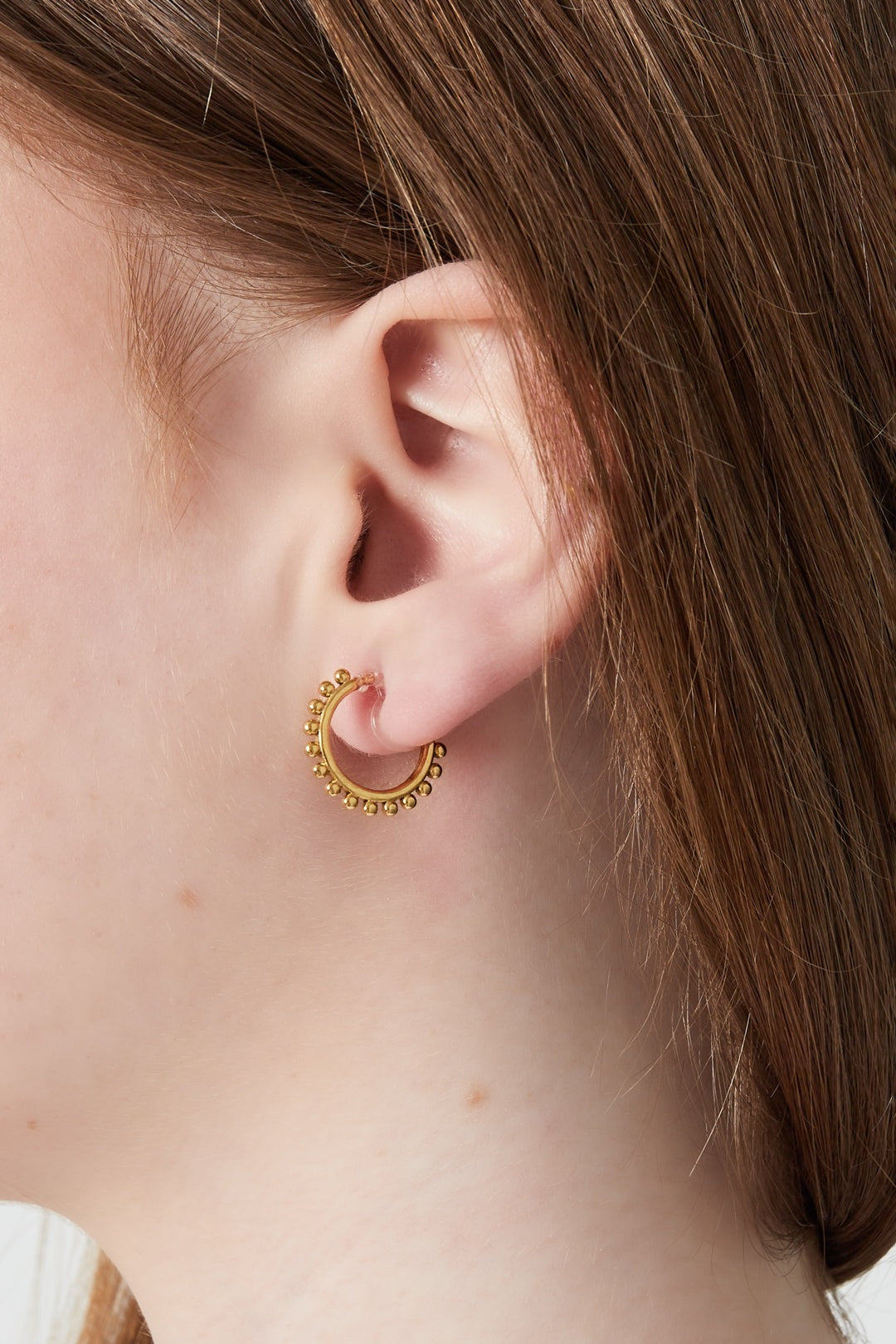 Close-up of a woman wearing the gold-tone beaded hoop clip-on earring on her left ear showcasing fit and style