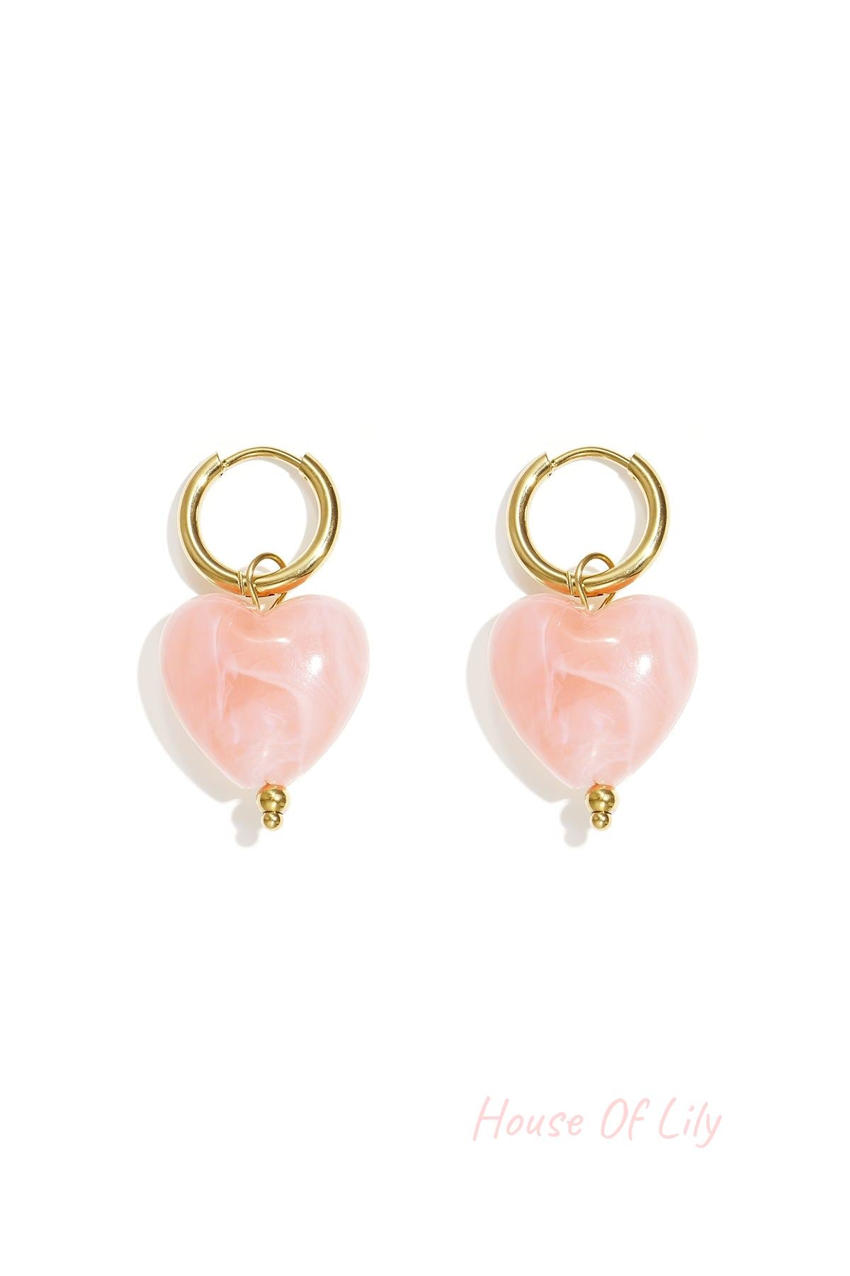 Pair of gold hoop earrings with glossy peach resin heart pendants on white background