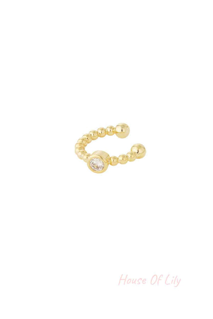 Close-up of a gold beaded ear cuff with a clear crystal centerpiece on white background