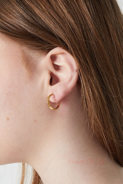 Close-up of a woman wearing a gold clip-on hoop earring featuring a sleek and simple design