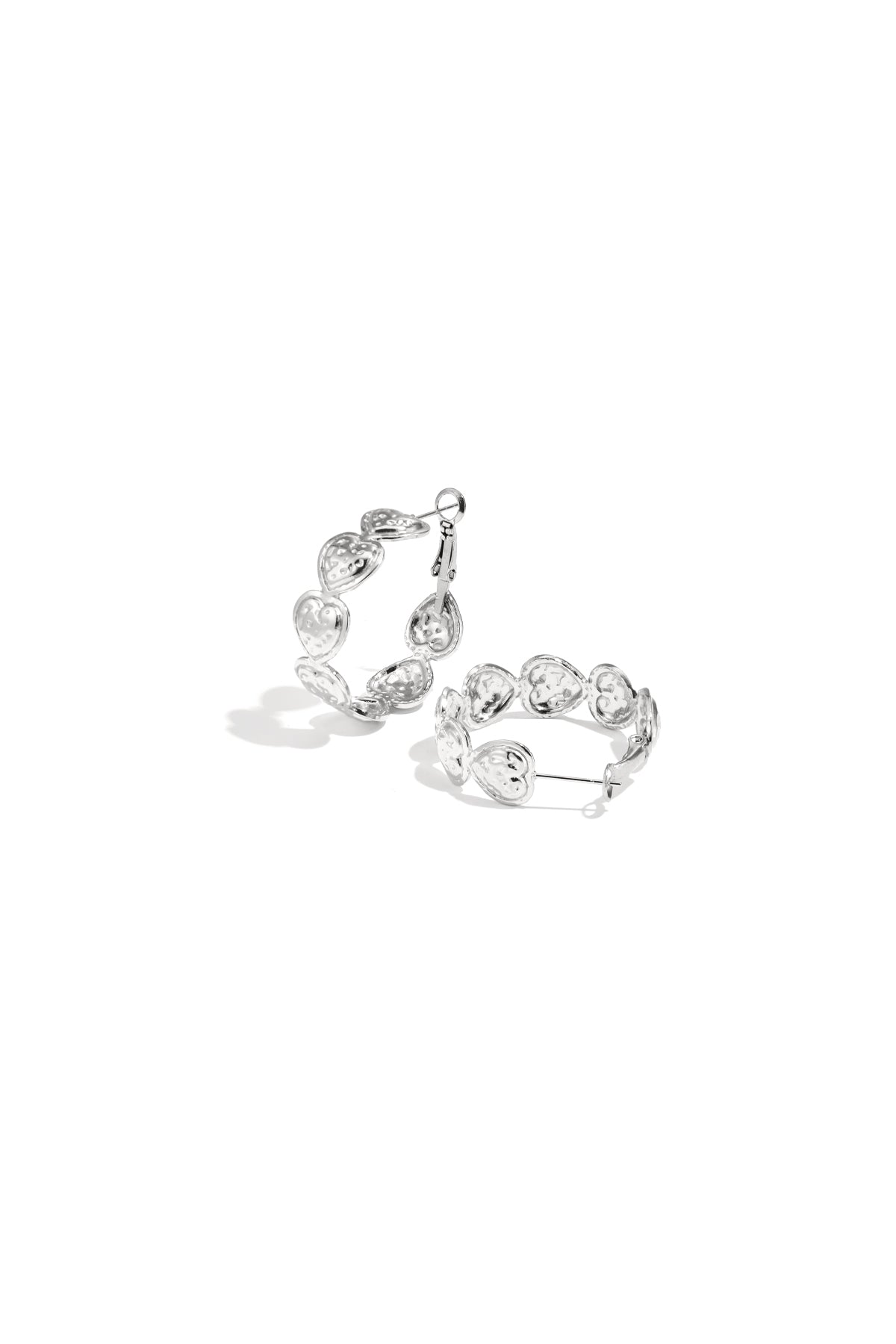 Pair of silver hoop earrings composed of small embossed hearts arranged in a circle on a white background