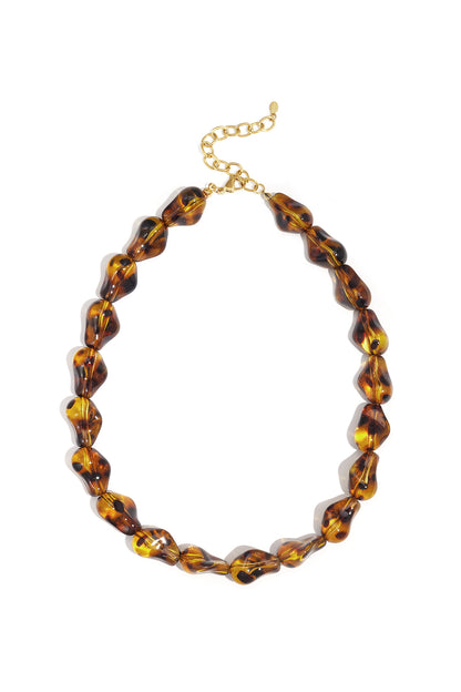Tortoiseshell patterned acrylic beaded necklace with gold chain clasp laid flat on white background
