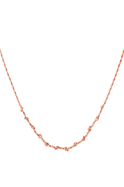 Coral and pink knotted cotton necklace with gold accents laid flat on white background