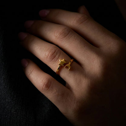 Gold open-style ring on a finger featuring a small star and crescent moon charm.