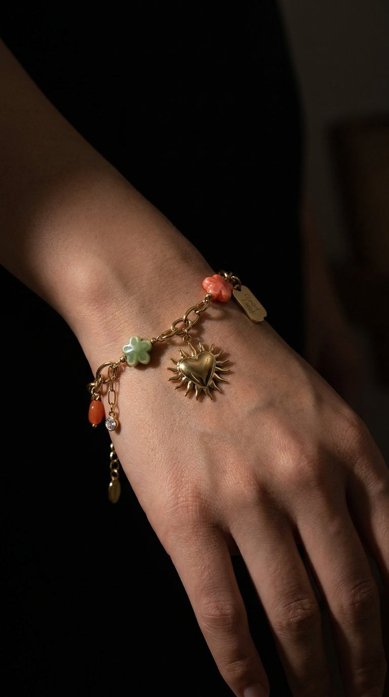 Charm Era Unlocked gold-tone charm bracelet featuring a sun-heart pendant, pastel flower beads, and stone accents.