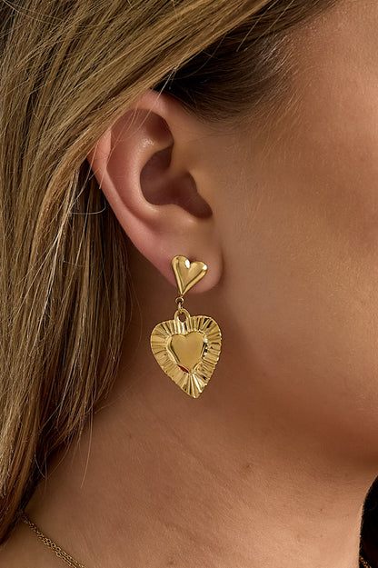Gold-tone heart drop earrings featuring intricate embossed detailing displayed on white background