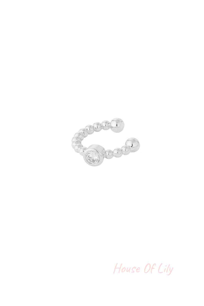 Close-up of a silver beaded ear cuff with a clear crystal centerpiece on white background