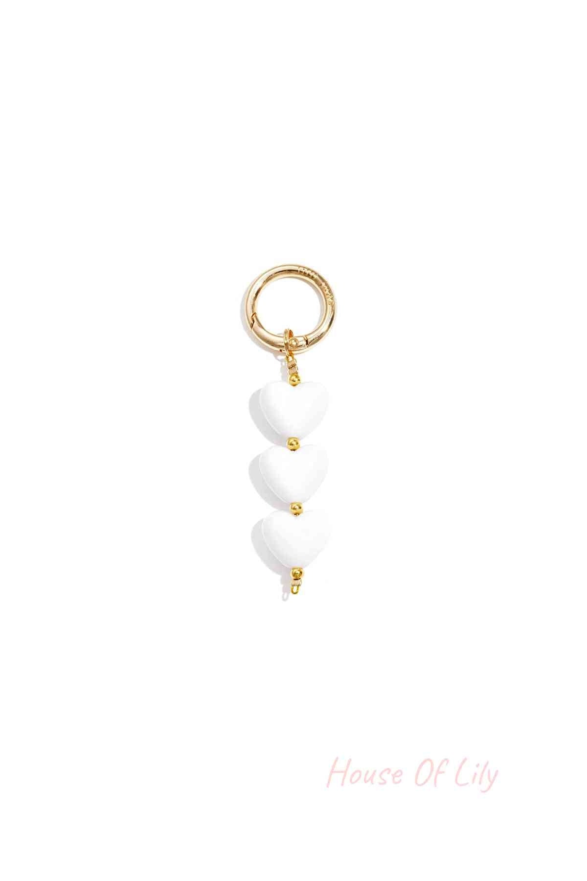 White acrylic heart charm bag keychain with gold-tone clasp on white background