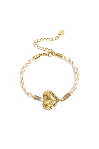 Close-up of a woman's hands touching her face showing off gold rings and multiple bracelets including the lavender flower charm bracelet