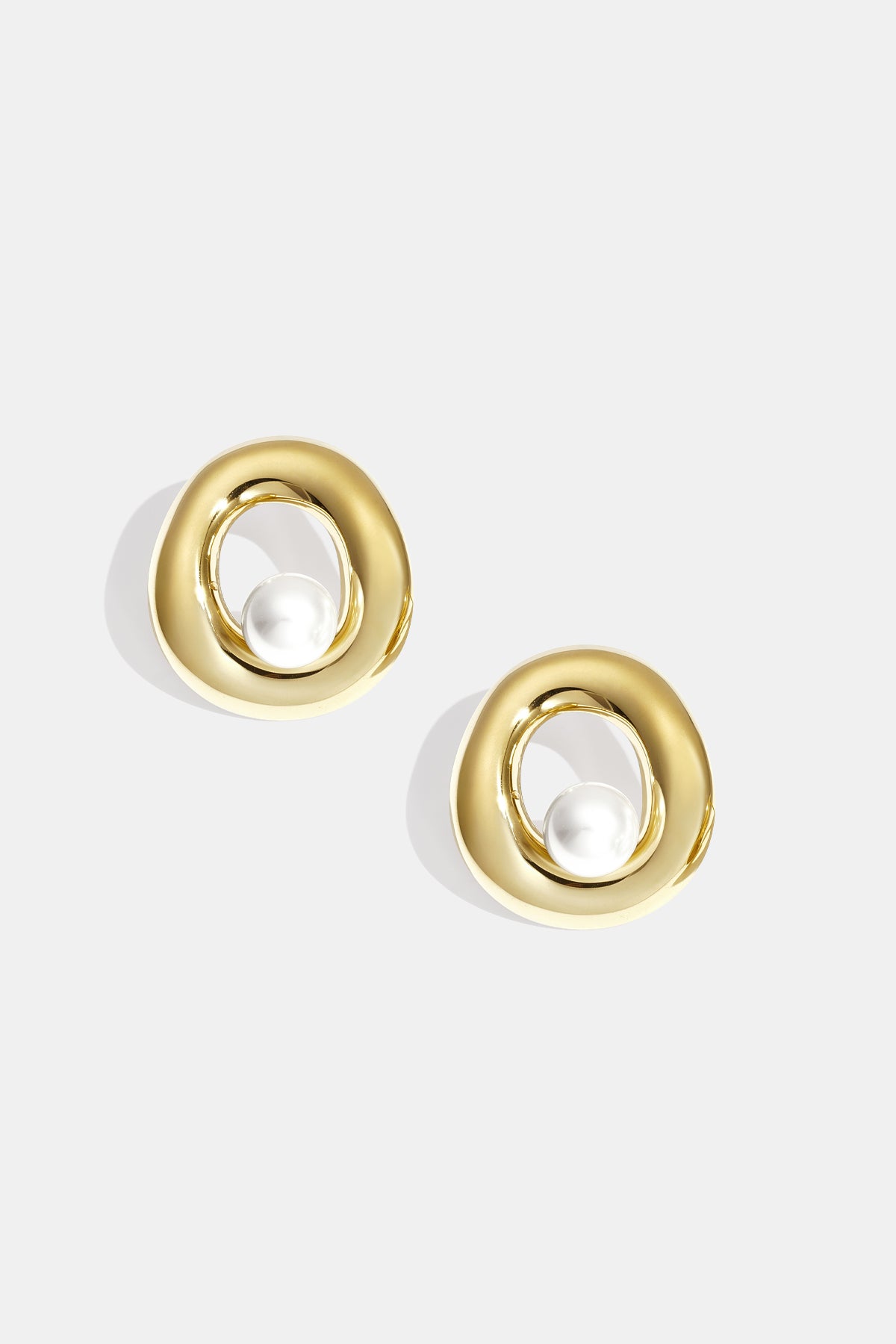 Pair of gold-tone circle stud earrings with pearl centerpiece on white background
