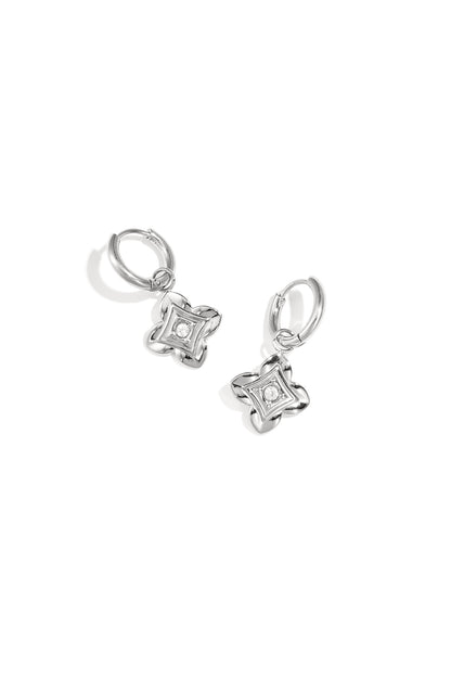 Close-up of silver floral drop earrings with zircon center on white background