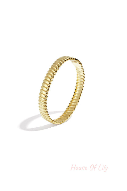 Close up of gold textured ribbed bangle jewelry on white background