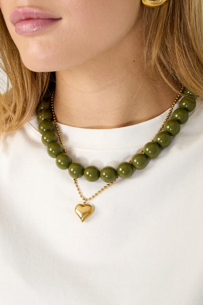Model wearing chunky beaded necklace featuring alternating blue and tortoise shell resin beads with gold clasp
