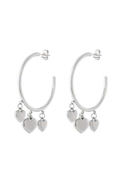 Pair of silver hoop earrings with three dangling heart-shaped charms on a white background.