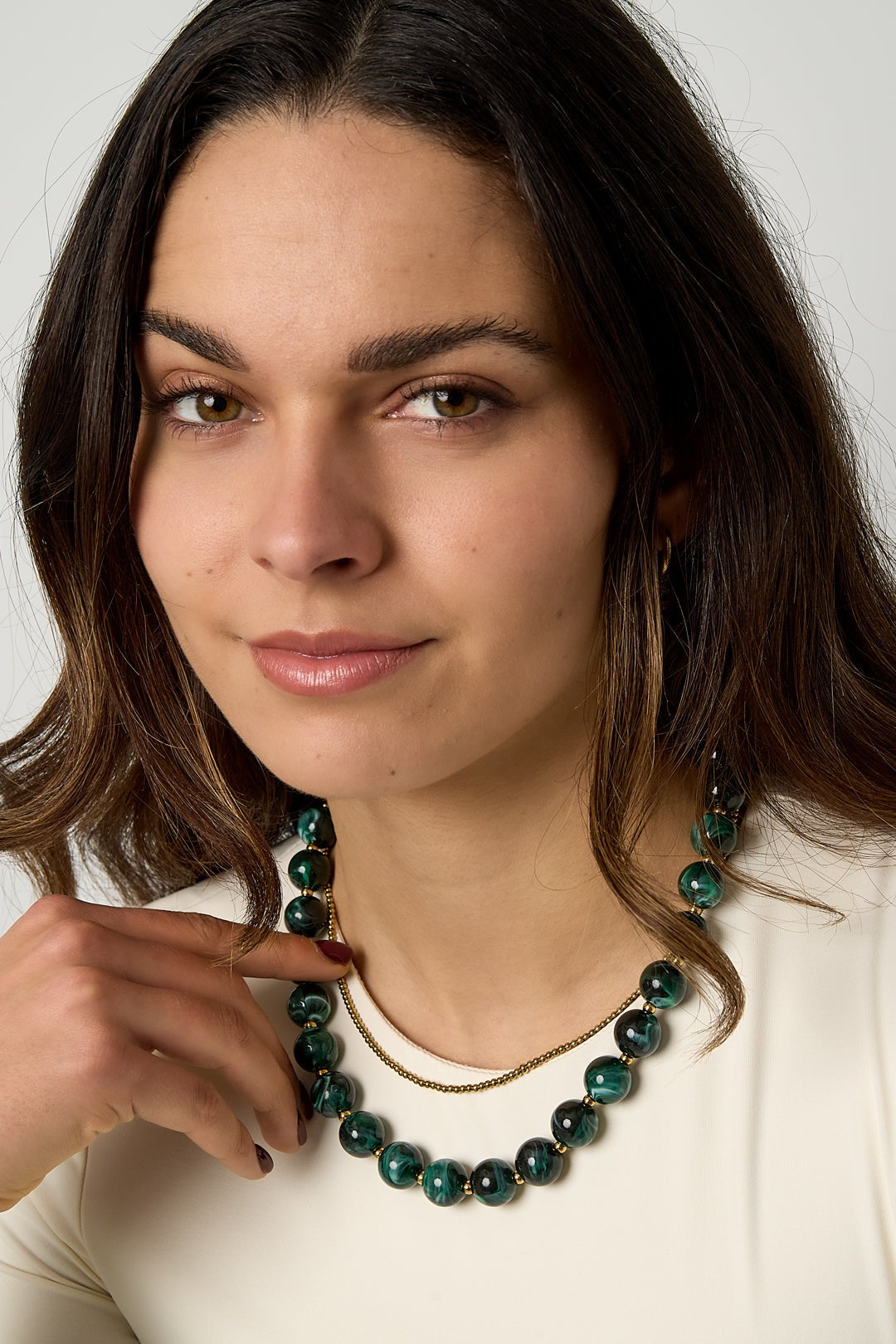 Woman wearing green marbled chunky beaded necklace layered with a delicate gold bead chain