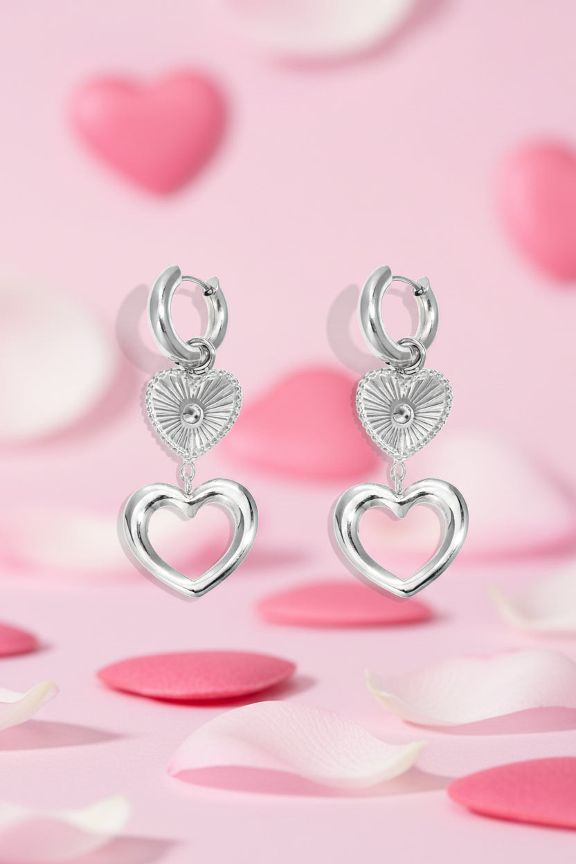 Pair of silver-toned heart charm hoop earrings with layered heart pendants on a white background